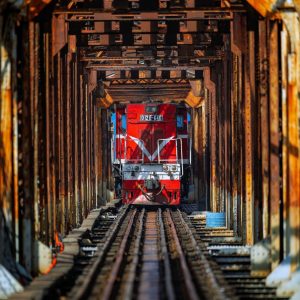 A scenic view of a Vietnam railway train crossing the Red River in Hanoi, showcasing historic rail transport in Vietnam